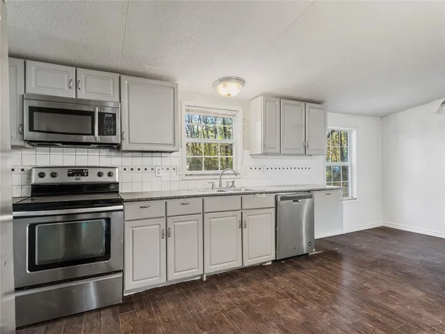 a kitchen with granite countertop cabinets stainless steel appliances and a window