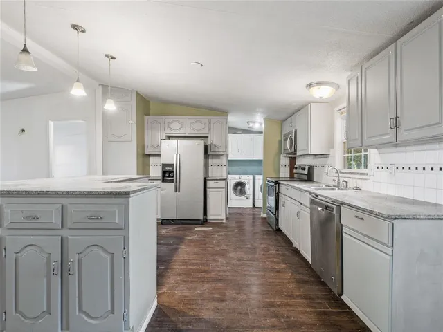 a large kitchen with cabinets a sink a counter space stainless steel appliances and cabinets
