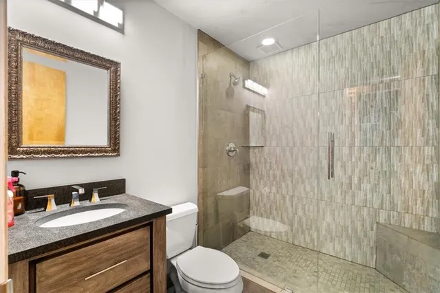 a bathroom with a granite countertop sink toilet a mirror and shower