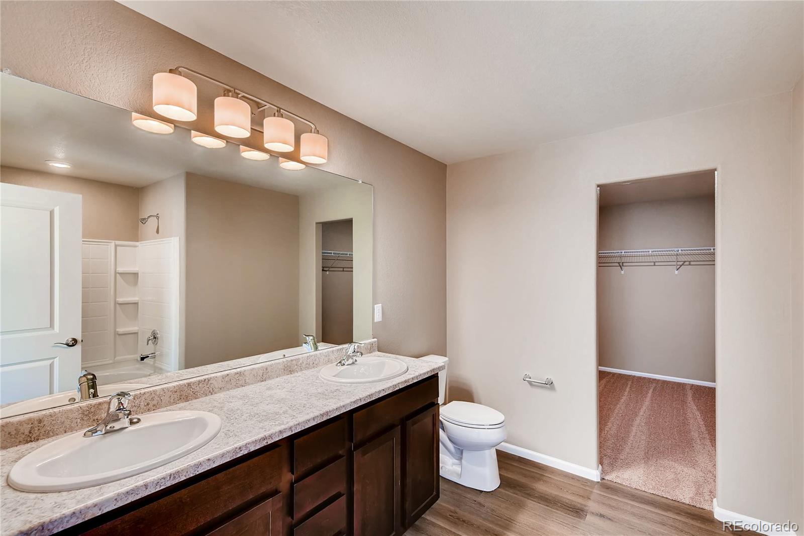 7132 Shavano Circle Frederick, CO 80504 - Photo 11 of 14 a bathroom with a granite countertop sink a toilet and a large mirror