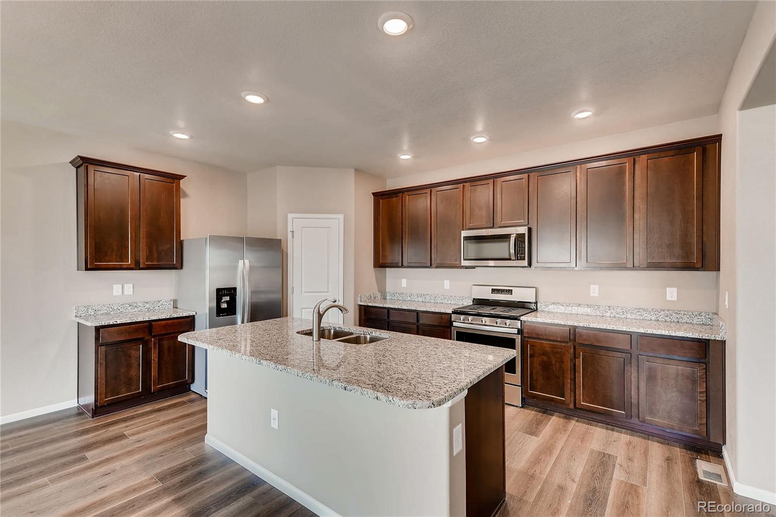 7132 Shavano Circle Frederick, CO 80504 - Photo 4 of 14 a kitchen with stainless steel appliances granite countertop a sink stove microwave and refrigerator