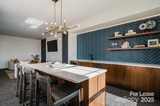 a kitchen with a stove a sink dishwasher a dining table and chairs with wooden floor