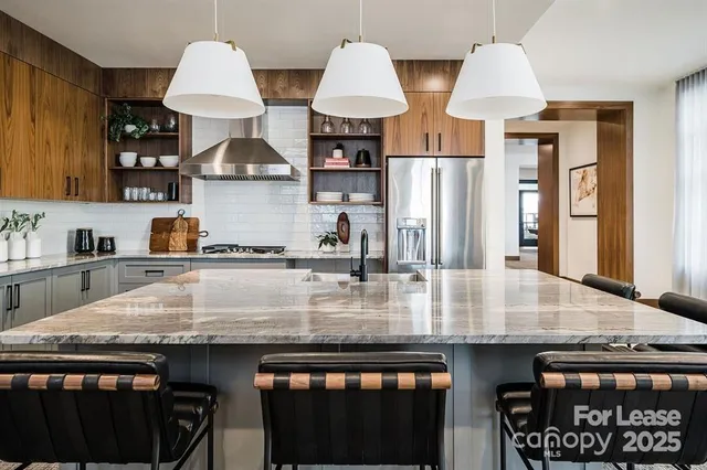 a kitchen with stainless steel appliances granite countertop a stove a sink a refrigerator and white cabinets with wooden floor