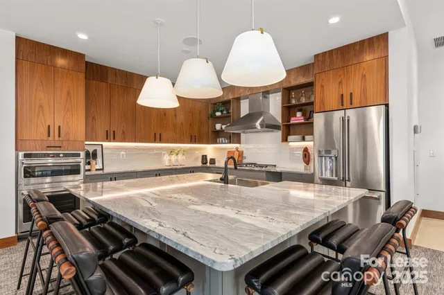 a kitchen with stainless steel appliances granite countertop a refrigerator a sink dishwasher a stove and white countertops with wooden floor