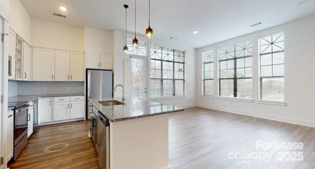 a kitchen with stainless steel appliances kitchen island a table chairs in it and wooden floors