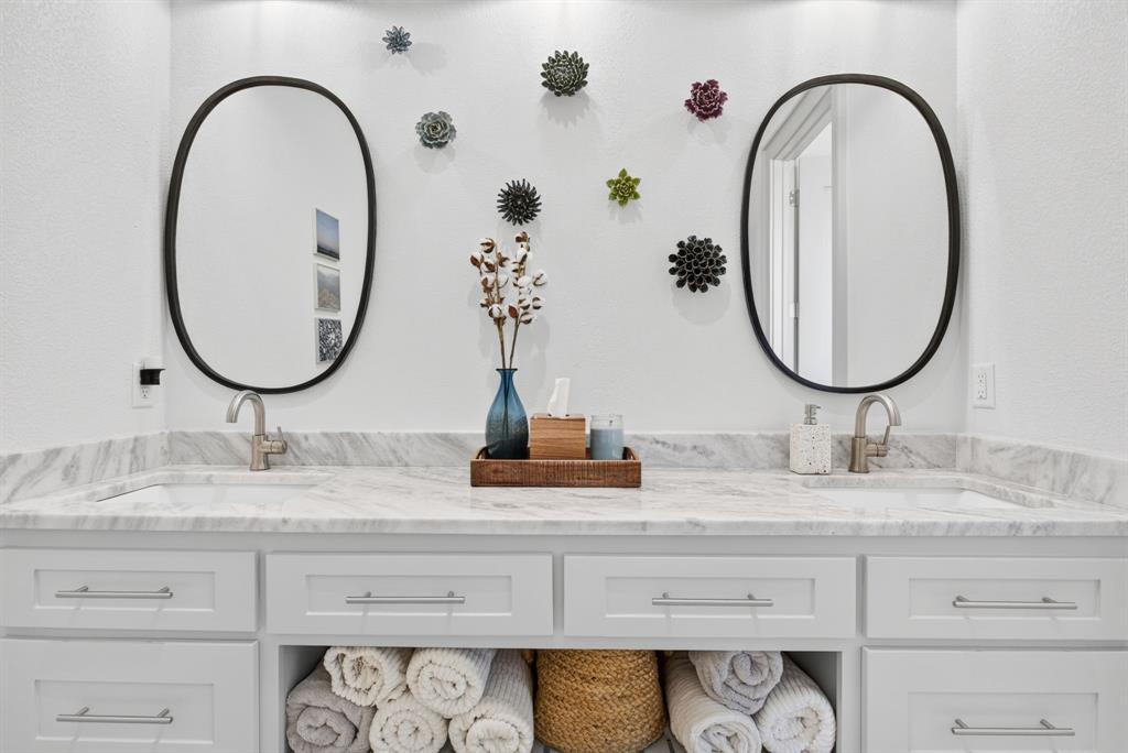 3008 Perkins Weatherford, TX 76088 - Photo 25 of 36 Double vanity featuring a marble-finish countertop, undermount sinks, and contemporary wall-mounted oval mirrors with black frames