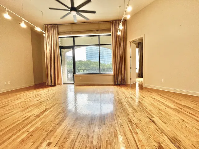 a view of empty room with wooden floor and fan