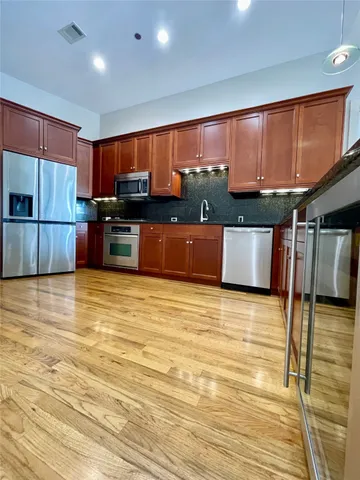 a kitchen with stainless steel appliances wooden cabinets a stove top oven a sink and dishwasher with wooden floor