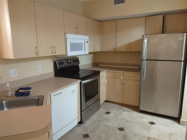 a kitchen with a refrigerator sink stove and cabinets