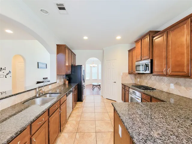 a large kitchen with stainless steel appliances granite countertop a large stove a sink and a microwave