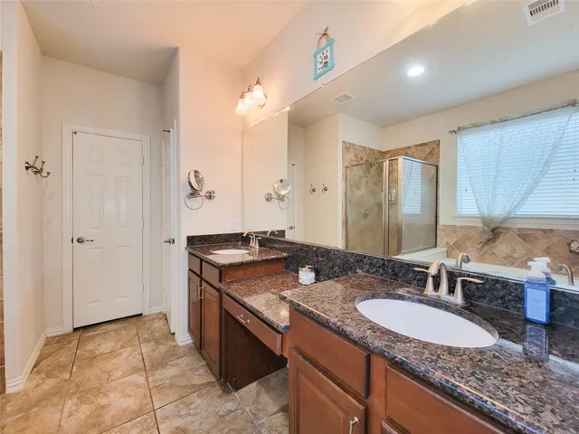 a bathroom with a granite countertop double vanity sink and a mirror