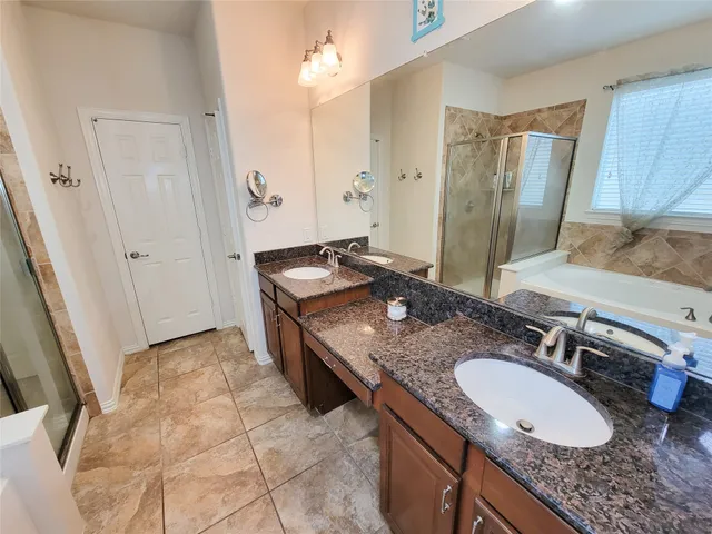 a bathroom with a granite countertop double vanity sink and a mirror