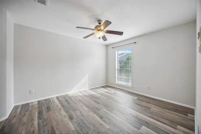 a view of a room with wooden floor ceiling fan and window