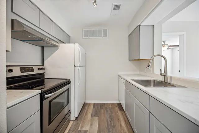 a kitchen with granite countertop a sink stove and refrigerator