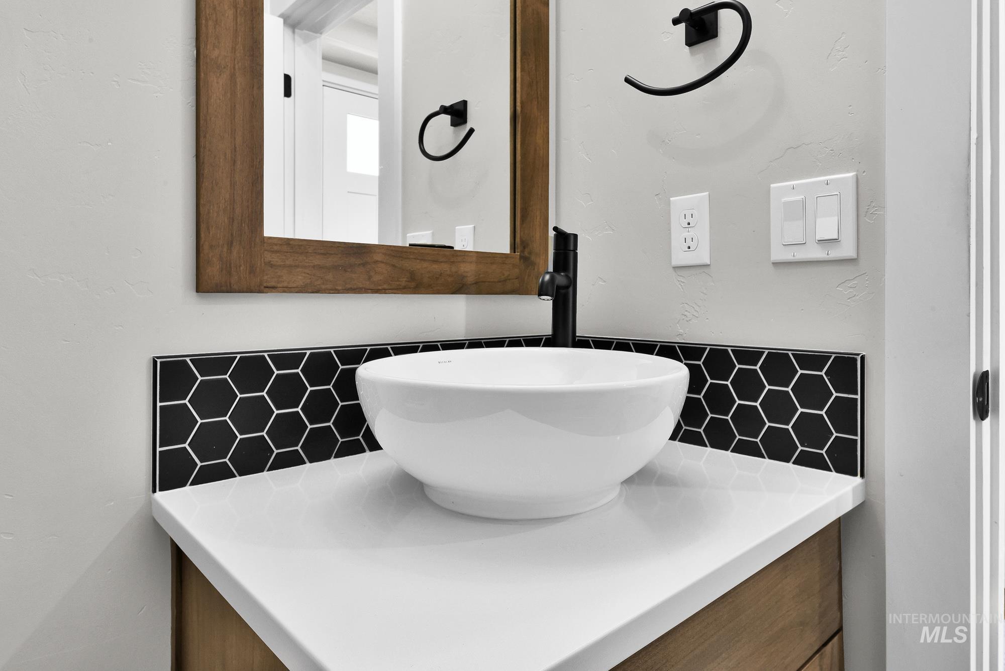 5676 East Zaffre Ridge Street Boise, ID 83716 - Photo 8 of 50 Modern vessel sink atop a crisp white countertop, complemented by a bold black hexagonal tile backsplash