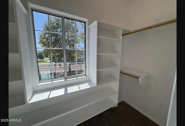 an empty room with a window and ceiling fan