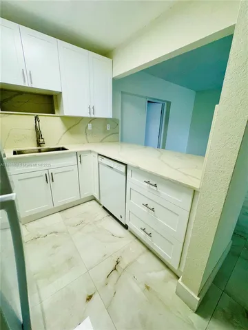 a kitchen with granite countertop white cabinets and white appliances