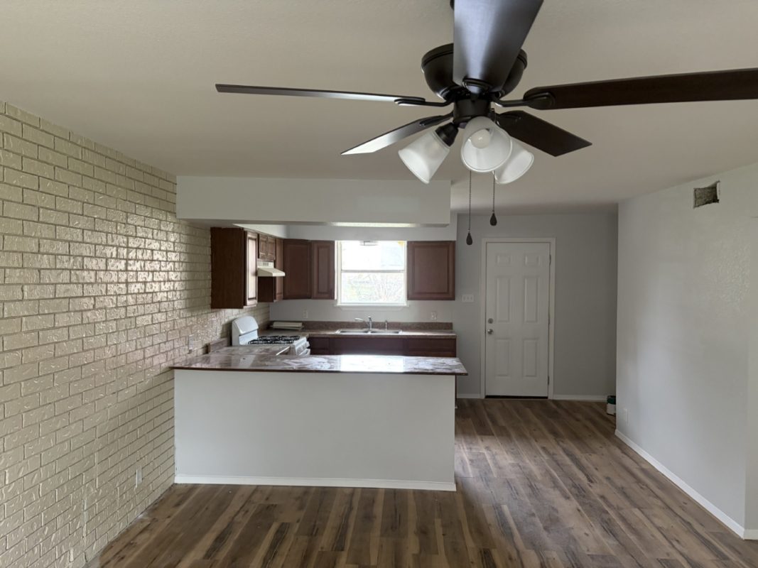 604 West 4th Street Taylor, TX 76574 - Photo 4 of 8 Kitchen with brick wall, a peninsula, white range with gas stovetop, dark wood-style floors, and a ceiling fan