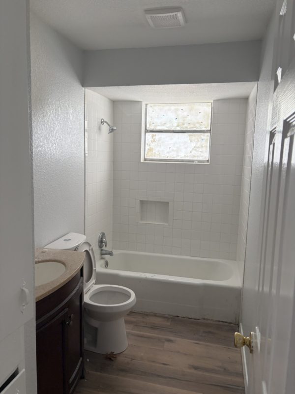604 West 4th Street Taylor, TX 76574 - Photo 8 of 8 Bathroom with vanity, shower / tub combination, dark wood-type flooring, and a textured wall