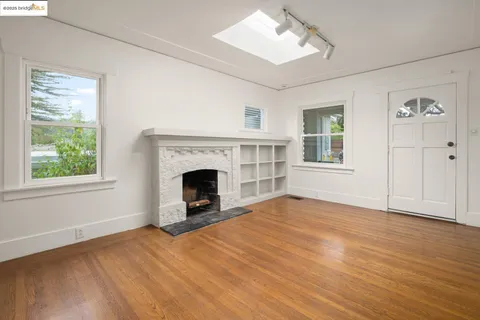 an empty room with windows fireplace and wooden floor