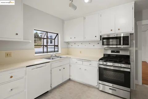 a kitchen with granite countertop white cabinets and appliances