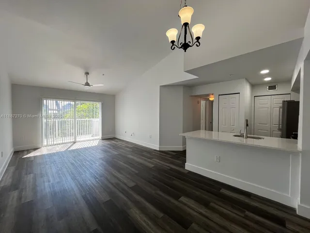 a view of a kitchen with a dishwasher a kitchen island wooden floor and a chandelier