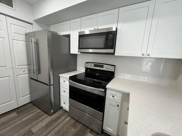 a kitchen with stainless steel appliances white cabinets and a wooden floor