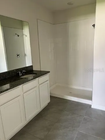 a bathroom with a granite countertop sink and white cabinets