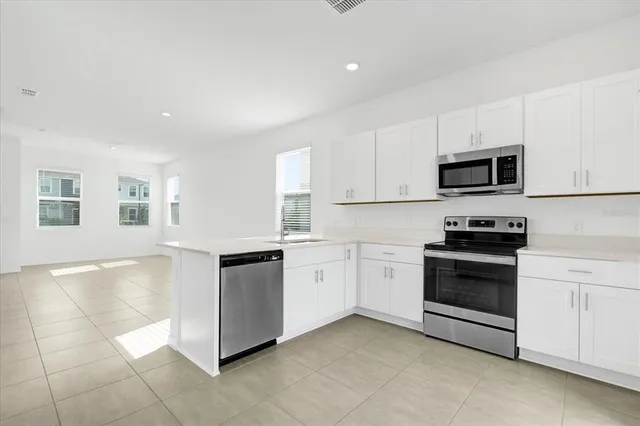 a kitchen with granite countertop white cabinets and stainless steel appliances