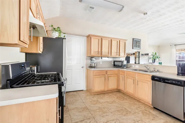 a kitchen with stainless steel appliances a stove a sink a refrigerator and cabinets