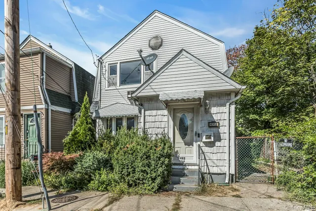 a view of a white house next to a yard