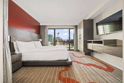 a bedroom with a large bed and a flat tv screen on dresser