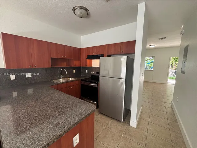 a kitchen with stainless steel appliances granite countertop a refrigerator a sink and a stove