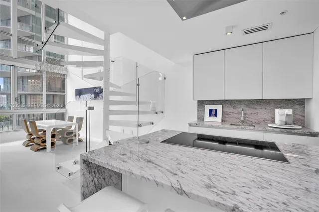 a large white kitchen with kitchen island a island a sink stainless steel appliances and cabinets