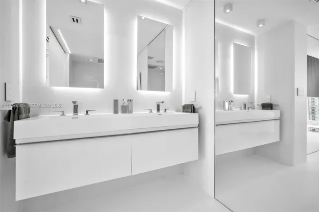 a bathroom with double vanity sinks a mirror and a bathtub
