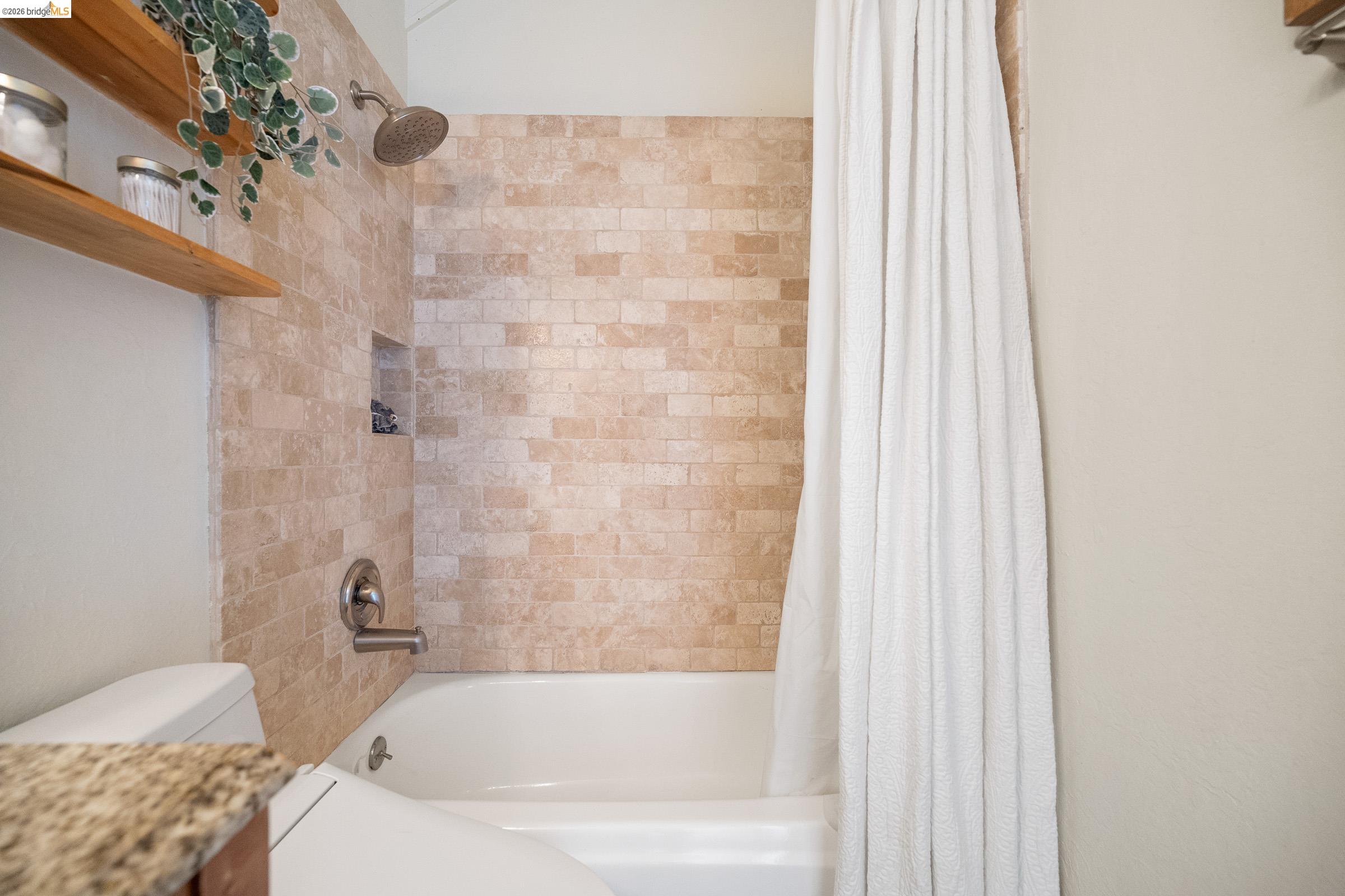 6600 Heather Ridge Way Oakland, CA 94611 - Photo 34 of 66 Subway tile shower surround with integrated soap niche, brushed nickel fixtures, and a soaking tub