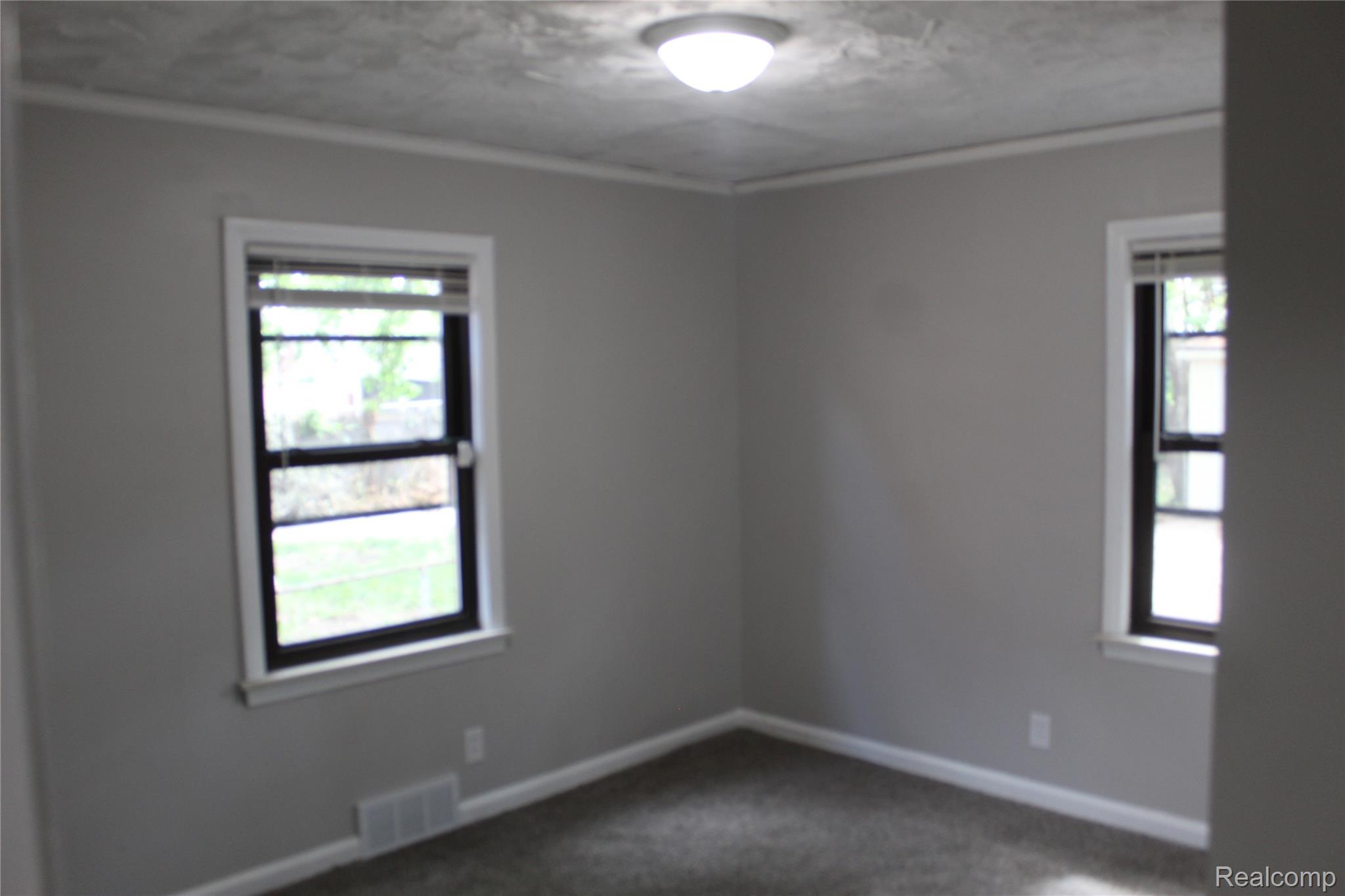 5543 Balfour Road Detroit, MI 48224 - Photo 14 of 54 Neutral-toned room featuring a ceiling-mounted light fixture, two windows with blinds, and perimeter crown molding