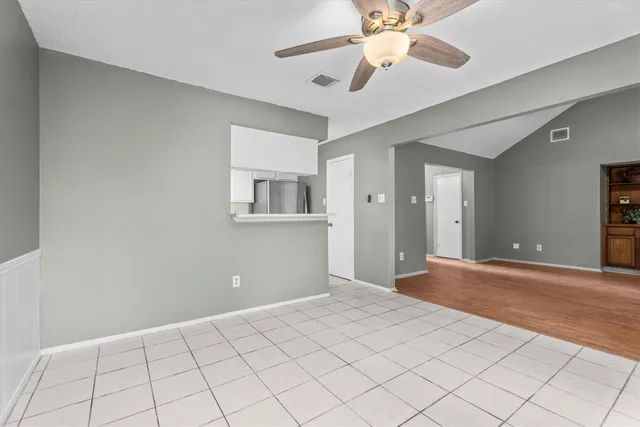 a view of an empty room with window and a chandelier fan