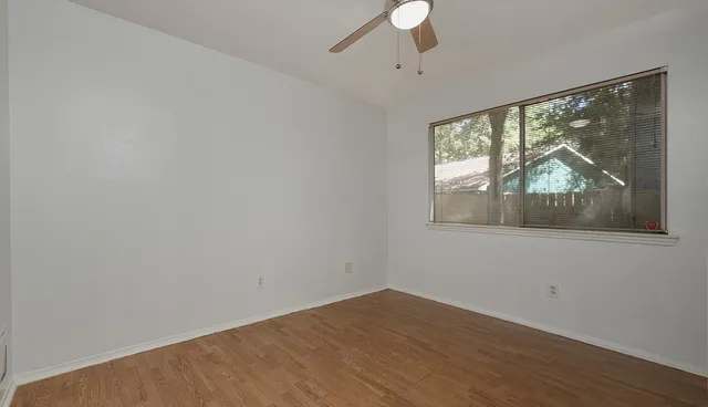 a view of empty room with wooden floor and fan
