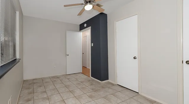 a view of an empty room with window and chandelier fan