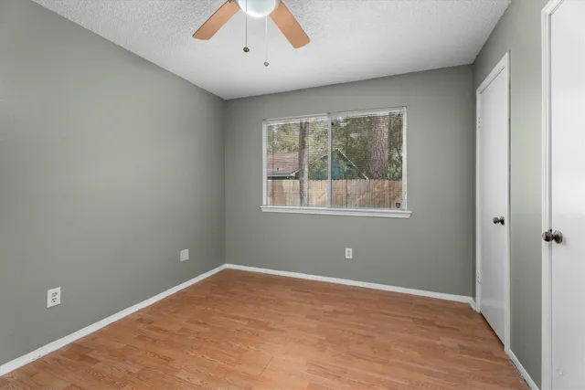a view of an empty room with wooden floor and a window