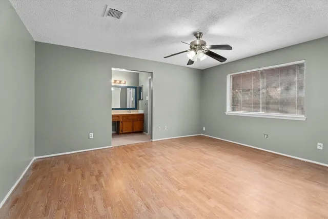 a view of empty room with wooden floor and ceiling fan