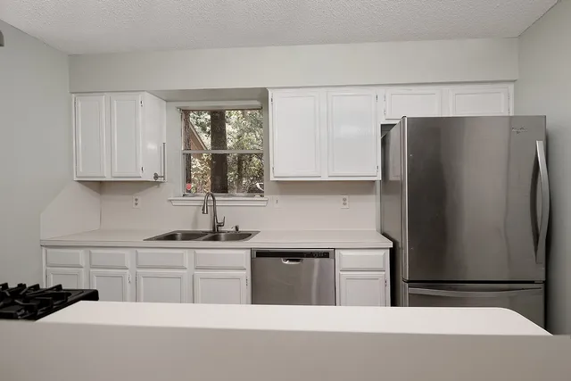 a kitchen with stainless steel appliances a refrigerator a sink and cabinets