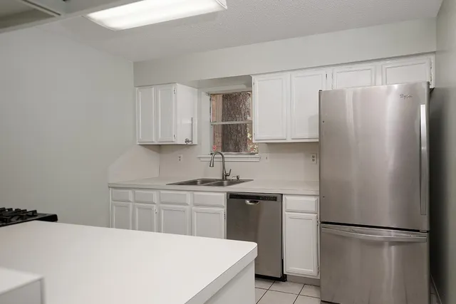 a kitchen with a refrigerator sink and cabinets