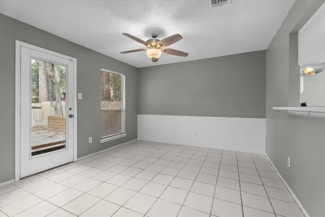 a view of an empty room with window and chandelier fan