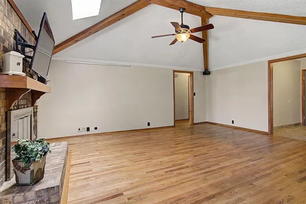a view of an empty room with wooden floor and a ceiling fan