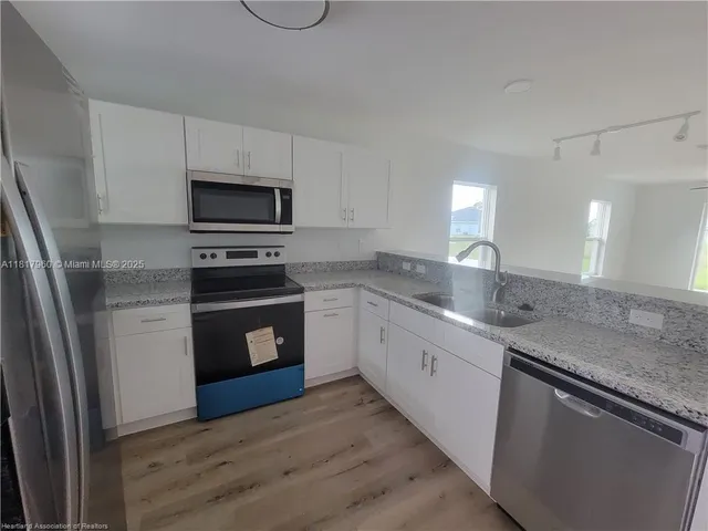a kitchen with granite countertop a refrigerator stove and sink