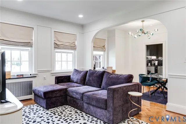a living room with furniture a flat screen tv and kitchen view