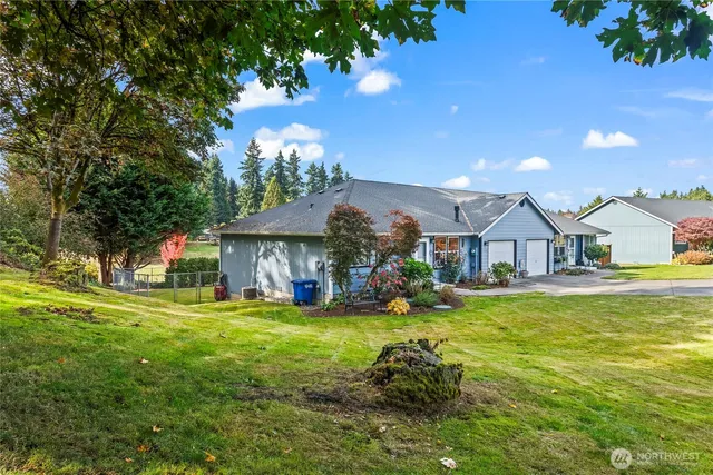 a view of a house with a big yard and large tree