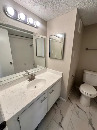 a bathroom with a granite countertop sink a toilet and a mirror